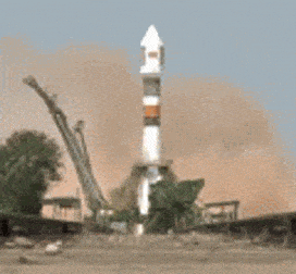 A white rocket having its launch towards space in the middle of the road. A cloud of dust can be seen in the background while the rocket launches.