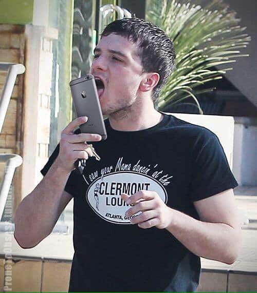 Josh Hutcherson licking the screen of his iPhone while holding keys.